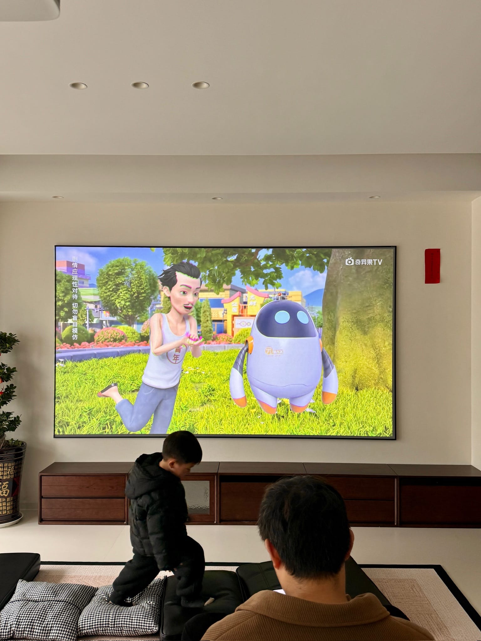 父亲和孩子在客厅固定大屏前一起观看动画